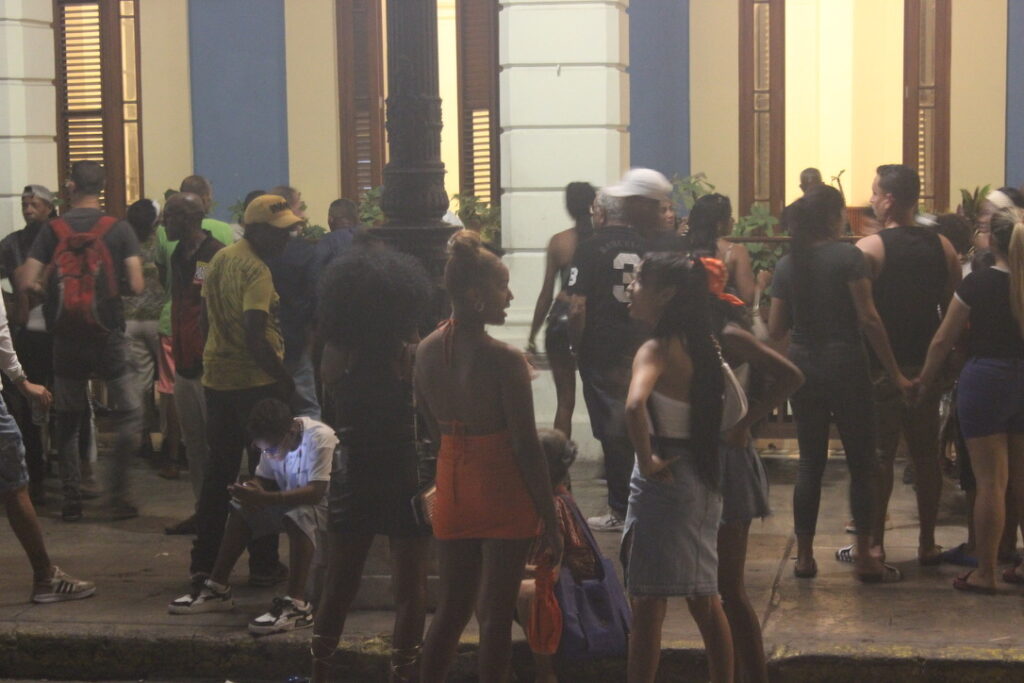 Jovens cubanos reunidos e conversando nas ruas de Havana Vieja durante a noite.