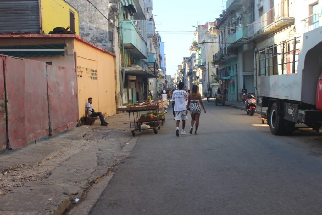 Vendedores empurrando carrinhos de frutas em uma rua residencial